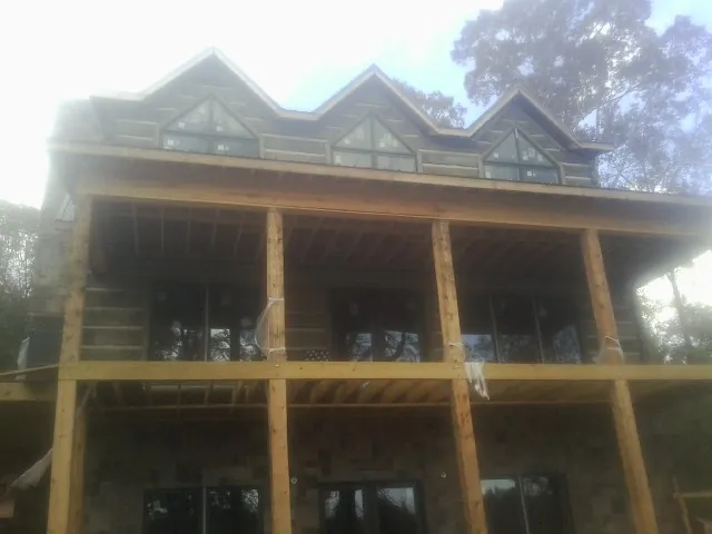 Dormers and porch framing on a large log home under construction — Roof Coating work by our crew in Filley