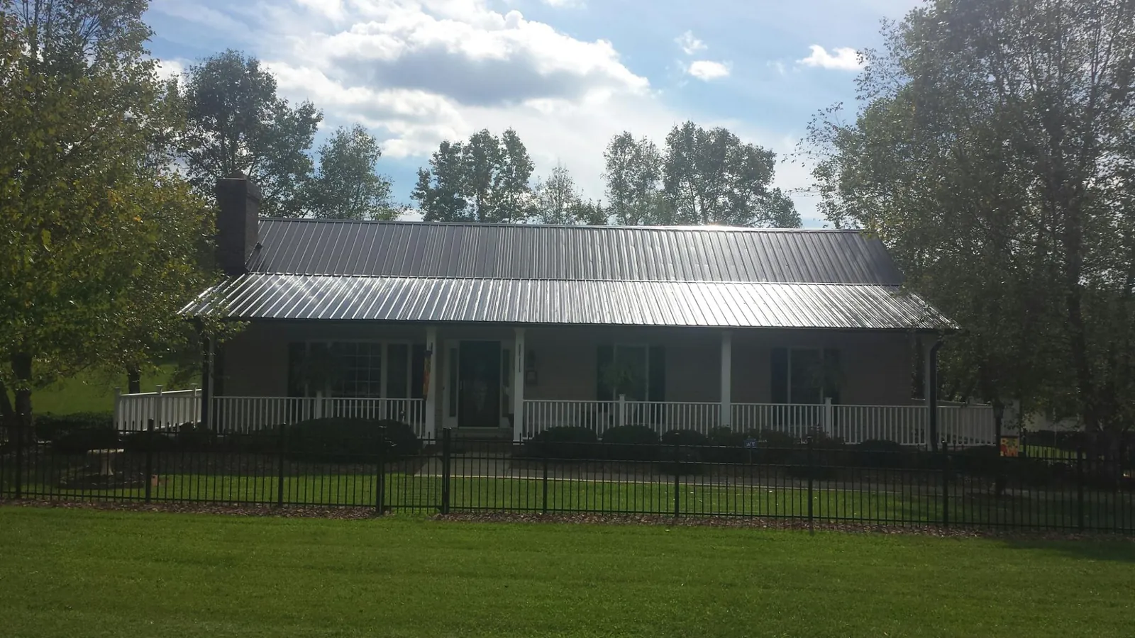 Gray metal roof on a brick ranch with a full width front porch — Gutter Guard Installation work by our crew in Filley