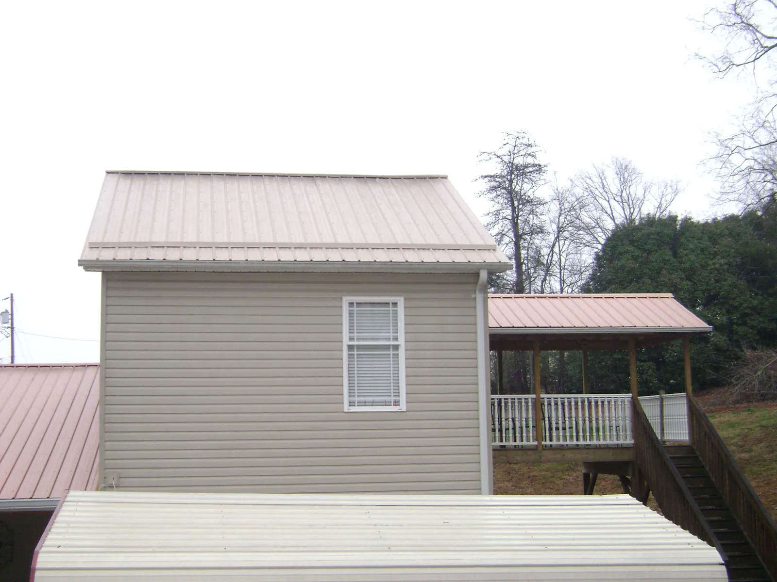 Tan metal roofs on a two story addition and attached porch, from a Roof Replacement job in Filley