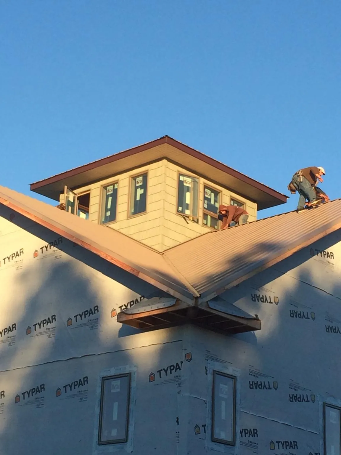 Roofers working around a rooftop cupola on a new metal roof at sunset — Roof Waterproofing in Filley by Roofing Brothers